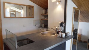 A modern kitchen with a large sink, a mirror, and a wooden ceiling.