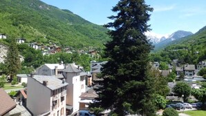 Un hotel con vistas a una cadena montañosa, rodeado de edificios residenciales y vegetación.