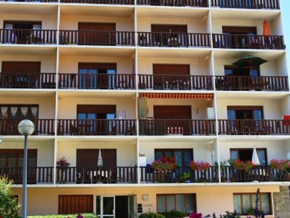 A multi-story hotel with balconies, each with wooden railings and potted plants.