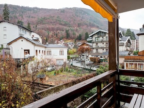 A balcony with a view of a residential area, including houses and a hillside.