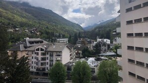 Un pueblo rodeado de montañas, con edificios bajo un cielo nublado.