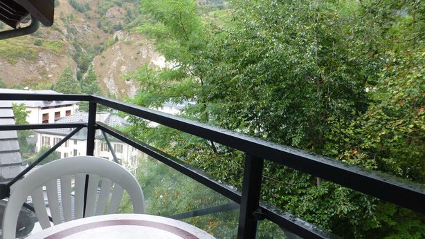 Uma varanda com vista para um vale e um edifício ao fundo.