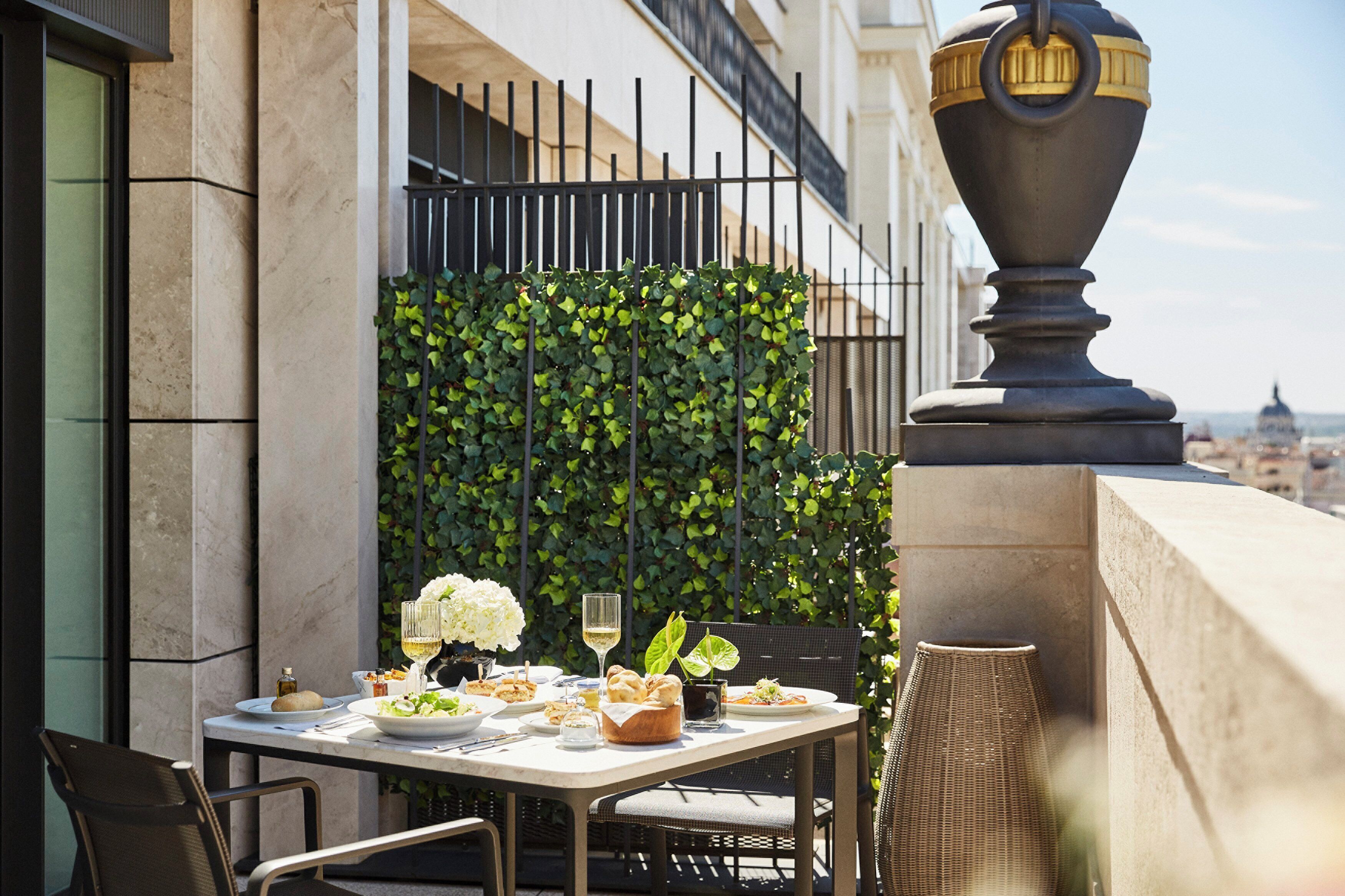 Un espace de restauration en plein air avec une table dressée pour un repas, entouré de verdure et agrémenté d’un vase décoratif.