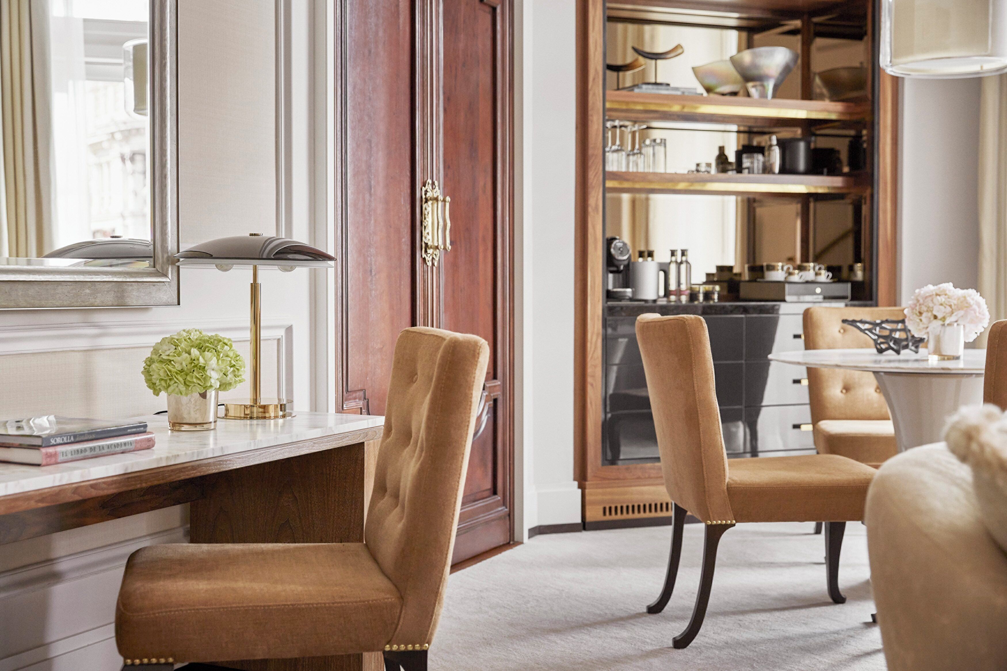 A modern kitchen with a built-in oven, a dining area with a table and chairs, and a large mirror above the counter.