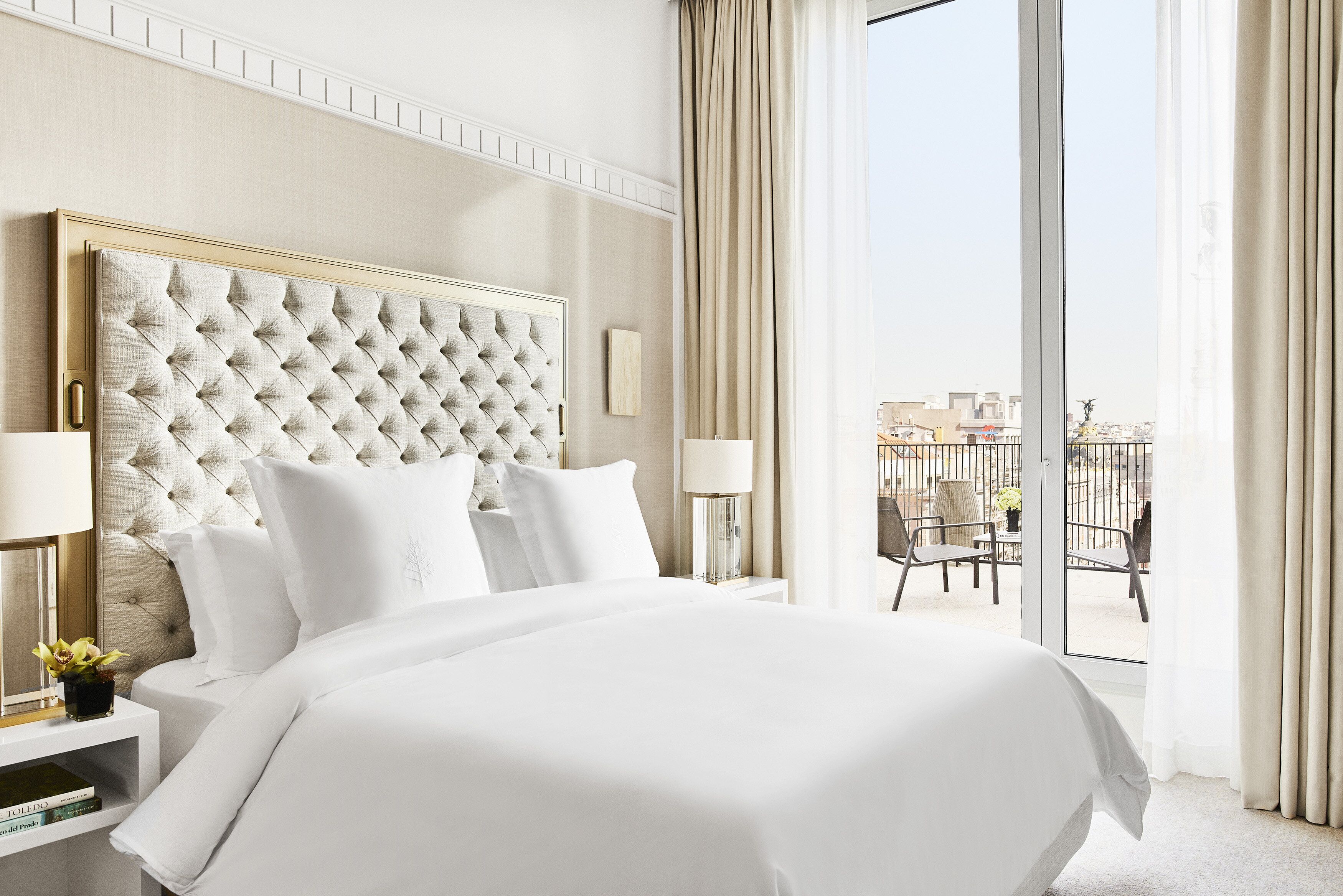 Une chambre d’hôtel avec un grand lit, une table de chevet avec une lampe et une vue sur la ville par une grande fenêtre.