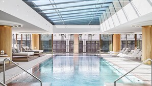 A modern indoor swimming pool with glass ceilings, sun loungers, and a view of the outside. - Four Seasons Hotel Madrid (Madrid)