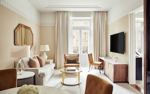 A modern living room with a sofa, armchairs, a coffee table, a TV, and a desk.