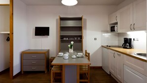 Una cocina compacta con una mesa de comedor, armarios de madera, microondas y cafetera.