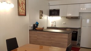 Uma cozinha compacta com uma mesa de jantar de madeira, micro-ondas, pia e geladeira.