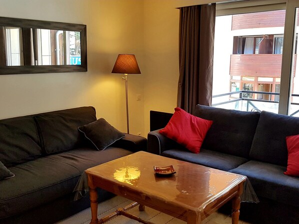 Ein Wohnzimmer mit einem dunkelgrauen Sofa, einem Holztisch und einer Stehlampe.