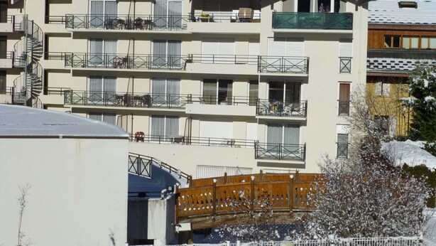 Um hotel com vários andares, varandas, um teleférico e paisagem coberta de neve.