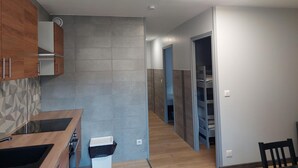 A modern kitchen with wooden cabinets, a built-in stove, and a trash bin.