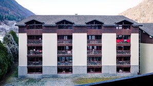 A multi-story hotel with balconies, set against a mountainous backdrop. - Studio in Brides-les-Bains with Balcony and WiFi (Brides-les-Bains)