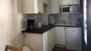 A compact kitchen with white cabinets, a microwave, a coffee maker, and a dishwasher. - Studio in Brides-les-Bains with Balcony and WiFi (Brides-les-Bains)