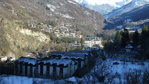 A mountainous village with snow-covered houses and a prominent building with a large window. - Studio in Brides-les-Bains with Balcony and WiFi (Brides-les-Bains)