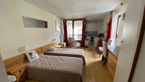 Une chambre d’hôtel avec deux lits, une petite kitchenette, un coin repas et une vue sur l’extérieur.
