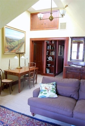 Relax in this inviting living room with a sofa, dining table, and bookshelf.