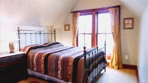 Une chambre à coucher avec un lit, une commode, une fenêtre avec des rideaux et un tableau au mur.