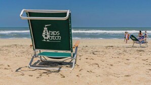A beach chair with 'Ships Watch' branding on a sandy beach. - Semi OF - CHEVEN at Ships Watch In Duck (Duck)