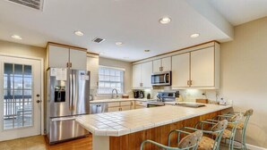 A modern kitchen with a central island, stainless steel appliances, and bar stools. - Semi OF - CHEVEN at Ships Watch In Duck (Duck)