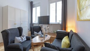 Een woonkamer met een zithoek, een salontafel, een televisie en een radiator.