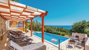 A poolside area with lounge chairs, a pergola, and a view of the sea. - 3 bedroom lovely apartment in Orebic (Orebic)