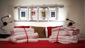 A hotel room with a bed, red bedding, two red pillows, a brown pillow, and a wall with four framed pictures. - THE CASINA OF SANT 'AGOSTINO (Colle di Val d'Elsa)