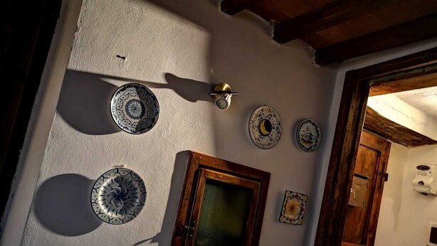 A room with a textured wall, a wooden door, and several decorative plates. - THE CASINA OF SANT 'AGOSTINO (Colle di Val d'Elsa)
