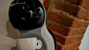 A coffee maker with a cup on top, placed on a wooden shelf against a brick wall. - THE CASINA OF SANT 'AGOSTINO (Colle di Val d'Elsa)