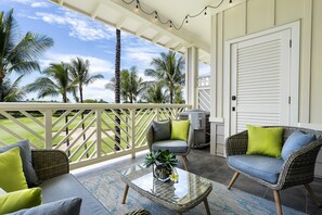 A covered porch with wicker furniture, a glass coffee table, and a view of palm trees and a lawn. - 🏖️Waikoloa Penthouse w/ Golf & Lake Views | Walk to A-Bay | Fairway Villas J34 (Waikoloa)