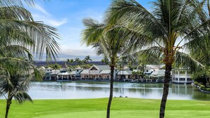 A golf course with a water body, palm trees, and buildings in the background. - 🏖️Waikoloa Penthouse w/ Golf & Lake Views | Walk to A-Bay | Fairway Villas J34 (Waikoloa)