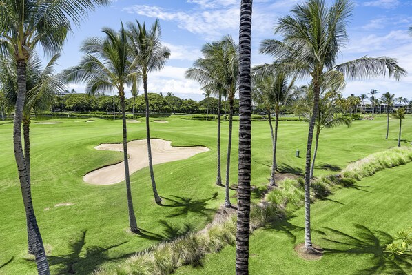 A golf course with palm trees, a sand bunker, and a well-maintained green. - 🏖️Waikoloa Penthouse w/ Golf & Lake Views | Walk to A-Bay | Fairway Villas J34 (Waikoloa)