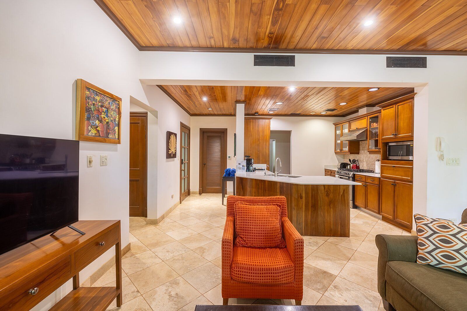 Una cocina moderna con armarios de madera, una isla central y un microondas integrado.