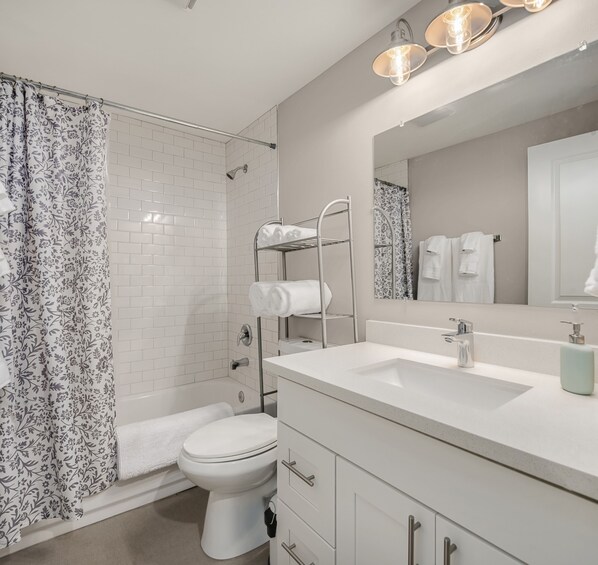 A modern bathroom with a shower, toilet, and vanity. - Spacious Main Street Retreat ~ Backyard ~ Parking! (Edmonds)