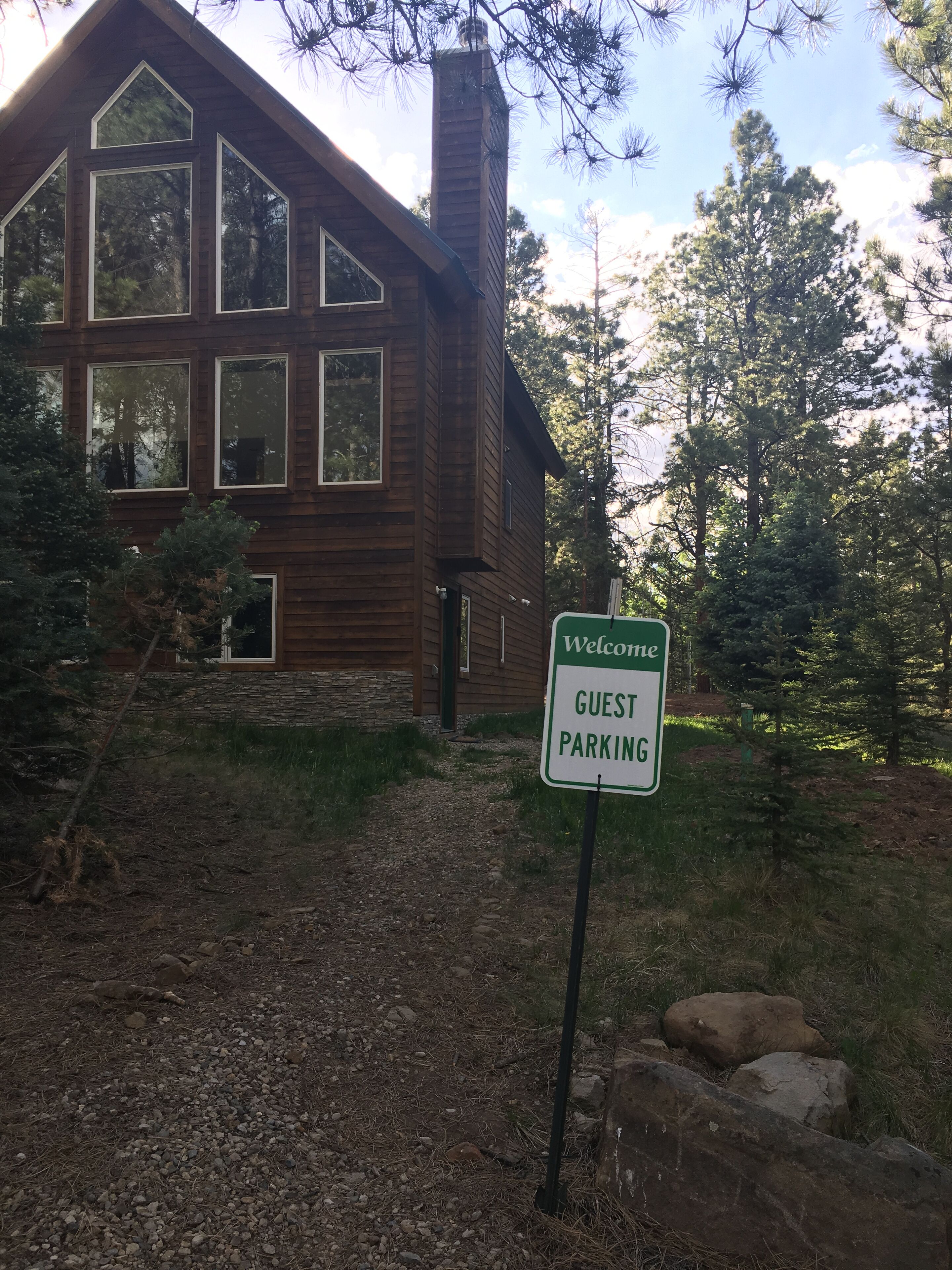 A wooden cabin with a 'Welcome Guest Parking' sign in front.