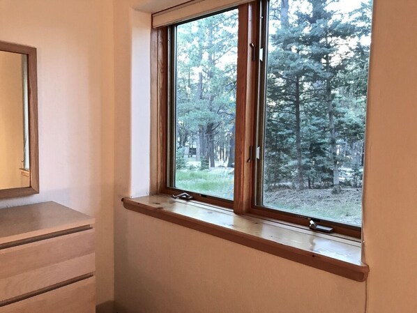 A room with a large window overlooking a forest. - Frnka Chalet Guest House (Taos)