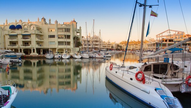 A marina with multiple boats docked, a large building with balconies, and a clear sky. - Albatros Beach Club (Benalmádena)