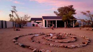 A circular stone arrangement in a desert setting with a building in the background. - Private stargazing retreat with Firepit/Views/ Spa/King bed (Joshua Tree)