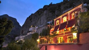 A building with multiple balconies and a red awning, surrounded by mountainous terrain. - ANTICO POSITANO - Five Bedroom Villa, Sleeps 9 (Positano)