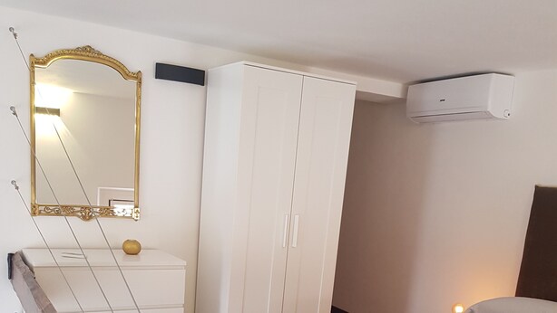 Quarto com cama, guarda-roupa, espelho e ar condicionado.