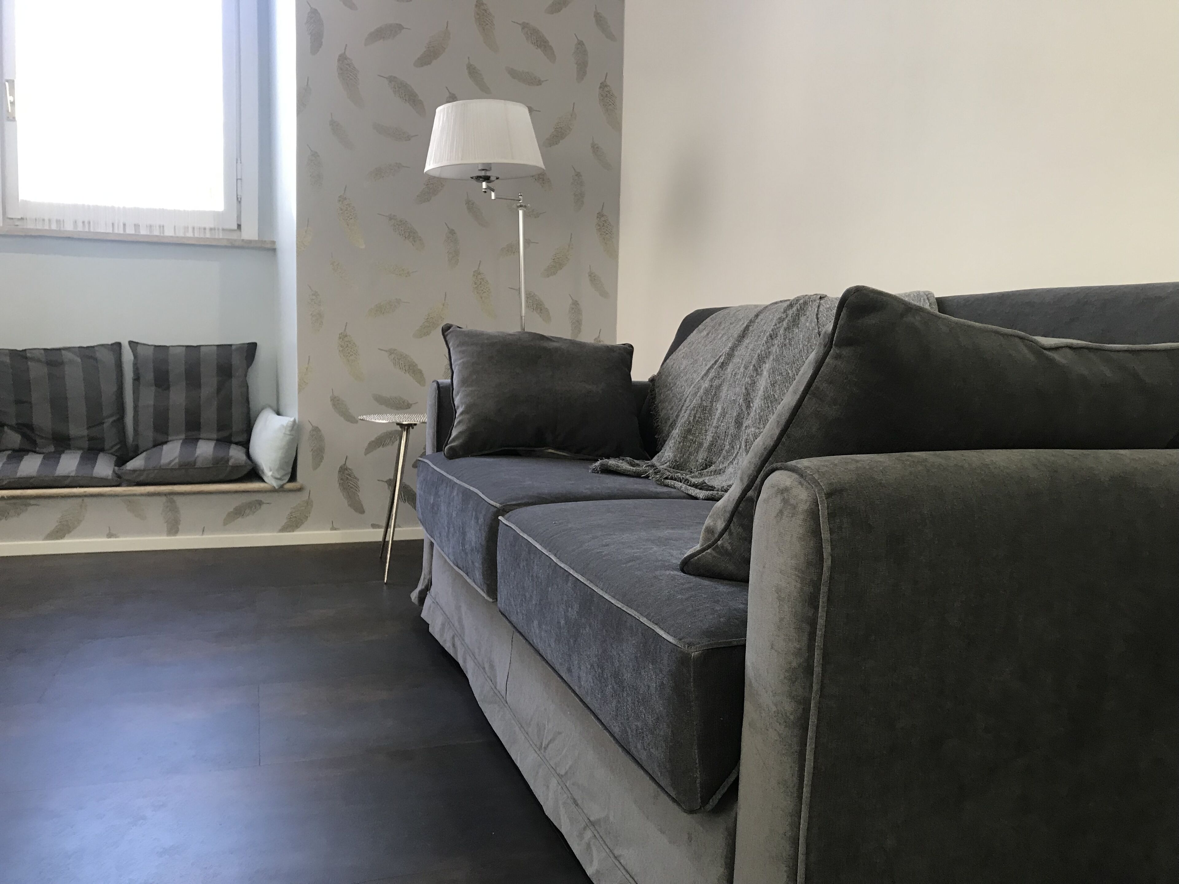 A modern living room with a grey sofa, a small side table, and a floor lamp.