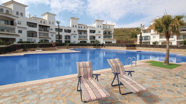 Ein Pool mit Liegestühlen, einem Rettungsring und einer Terrasse mit Steinplatten.