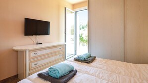 A hotel room with a bed, a dresser, a television, and a sliding glass door to the outside. - Pet friendly home in Borgo (Borgo)