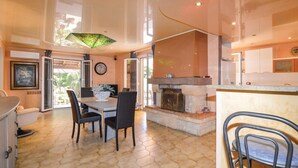 A spacious living area with a dining table and chairs, a fireplace, and a large window providing natural light. - Pet friendly home in Borgo (Borgo)