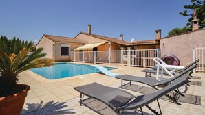 A pool area with lounge chairs, a fenced patio, and a building with a tiled roof. - Pet friendly home in Borgo (Borgo)