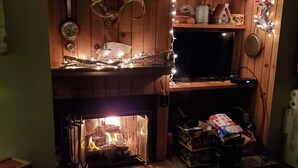 A cozy living room with a fireplace, wooden shelves, and a television. - Waterville Estates NH (Campton)