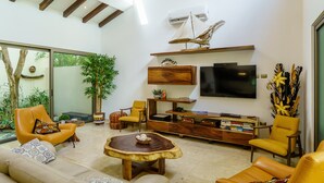 Una sala de estar moderna con un televisor grande, asientos cómodos y una mesa de centro de madera.