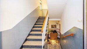 A staircase with a wooden handrail, a tiled floor, and a wall-mounted light fixture. - 2 bedroom awesome apartment in Crikvenica (Crikvenica)