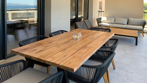 A wooden dining table with six chairs, a sofa, and a view of the sea. - New! Luxury apartment in Pietrosella at 300 m from the beach (Pietrosella)