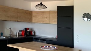 A modern kitchen with a central island, black and wooden cabinetry, a black refrigerator, and a hanging light fixture. - New! Luxury apartment in Pietrosella at 300 m from the beach (Pietrosella)